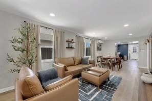 A modern living room with a sofa, ottoman, and dining table. - La Esperanza Unit A Central San Diego Getaway with AC (National City)