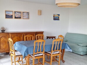 Un coin repas avec une table dressée pour quatre personnes, des chaises en bois, un buffet et un canapé.