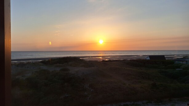 A sunset over a beach with dunes and a fence in the foreground. - Oceanfront—Panoramic view and beach access in Ste Cécile (Camiers)