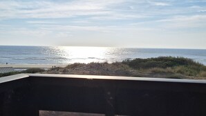 A beach view from a balcony with a railing, ocean, and a clear sky. - Oceanfront—Panoramic view and beach access in Ste Cécile (Camiers)