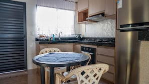 Eine kompakte Küche mit Esstisch, Stühlen, einem Kühlschrank und einem Fenster mit Blick.