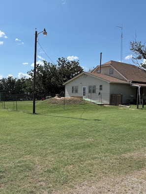 A house with a sloped roof, a fenced yard, and a clear sky.