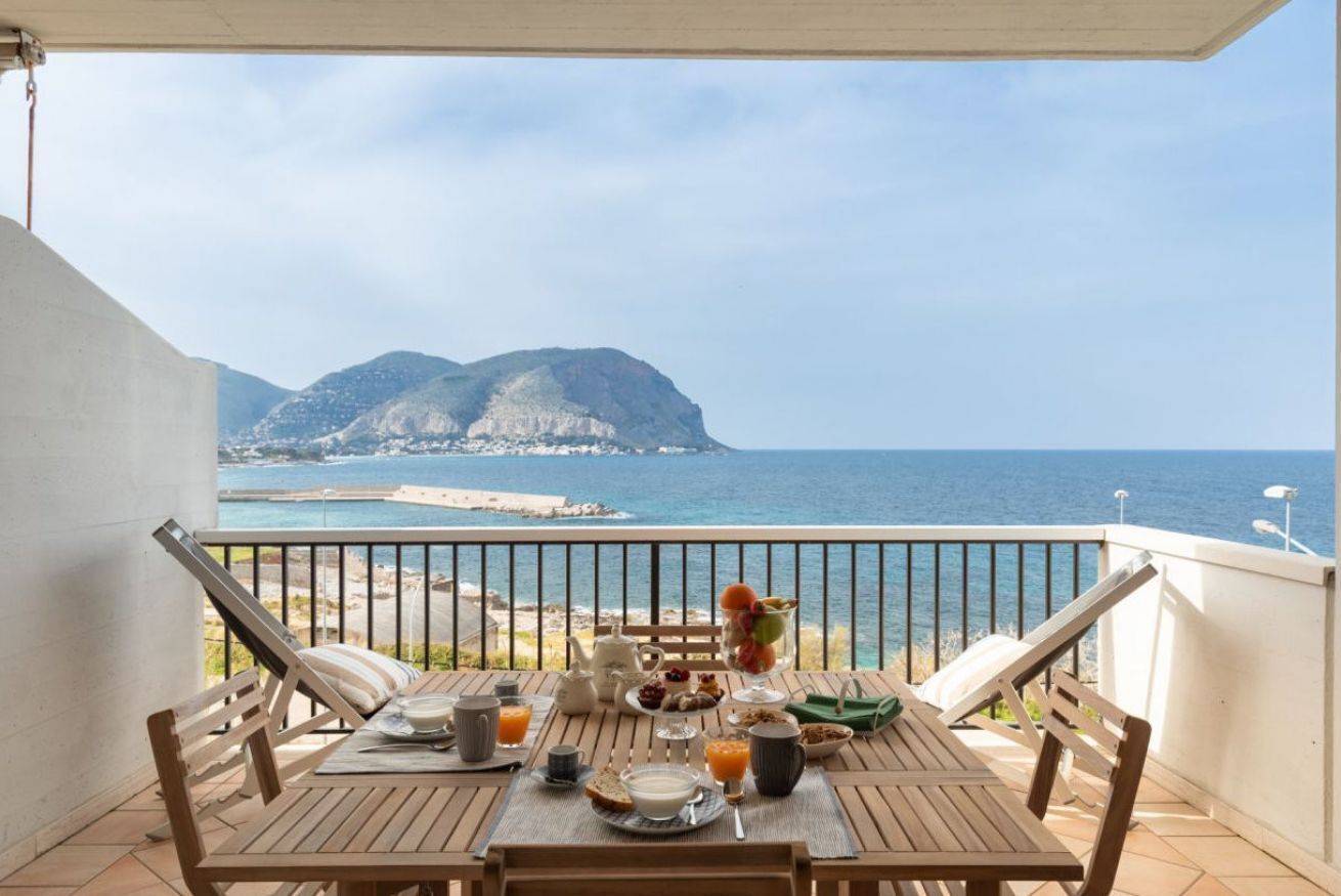 A wooden table set with breakfast items and a view of the sea and mountains.