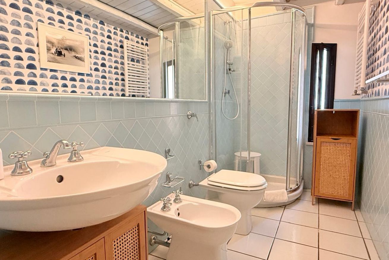 A bathroom with a large sink, a toilet, a bidet, and a glass-enclosed shower.
