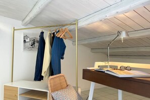 A room with a white desk, a chair, a hanging clothes rack, and a lamp. - Mondello in Terrazza | Panoramic Sea View (Palermo)