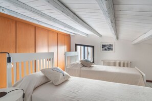 A bedroom with two beds, wooden wardrobe, white walls, and a window. - Mondello in Terrazza | Panoramic Sea View (Palermo)