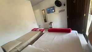 A room with two beds, a wall-mounted TV, a fan, and a door with a number. - Pousada cachoeira  (Paraty)