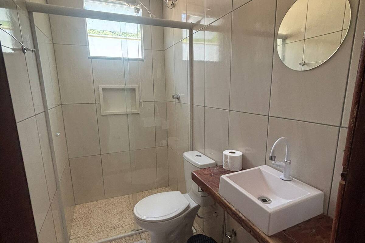 A small bathroom with a toilet, sink, mirror, and shower.