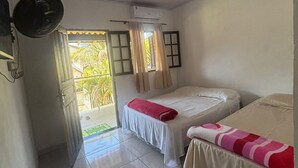 A room with two beds, a ceiling fan, an air conditioning unit, a small table with a remote control, and a door leading to a balcony. - Pousada cachoeira  (Paraty)
