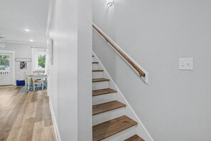 Eine Treppe mit Holzboden und Geländer, die zu einem Raum mit weißer Wand und einer Tür führt.