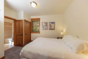 Ein Schlafzimmer mit einem Bett, einem Holzschrank, einer Duschkabine und zwei gerahmten Bildern an der Wand.