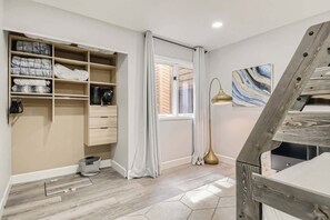 Ein Zimmer mit Einbauschrank, einem Vorhangfenster, einer Stehlampe und einem Bild an der Wand.