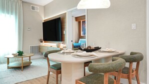 Ein Essbereich mit einem runden Tisch, Stühlen und einem Fernseher im Hintergrund.