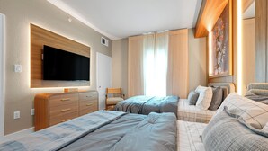 Ein Schlafzimmer mit zwei Betten, einem an der Wand befestigten Fernseher und einem Fenster mit Vorhängen.
