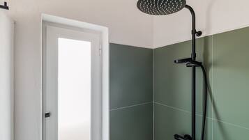Un bagno con doccia, una porta e pareti verdi e bianche.