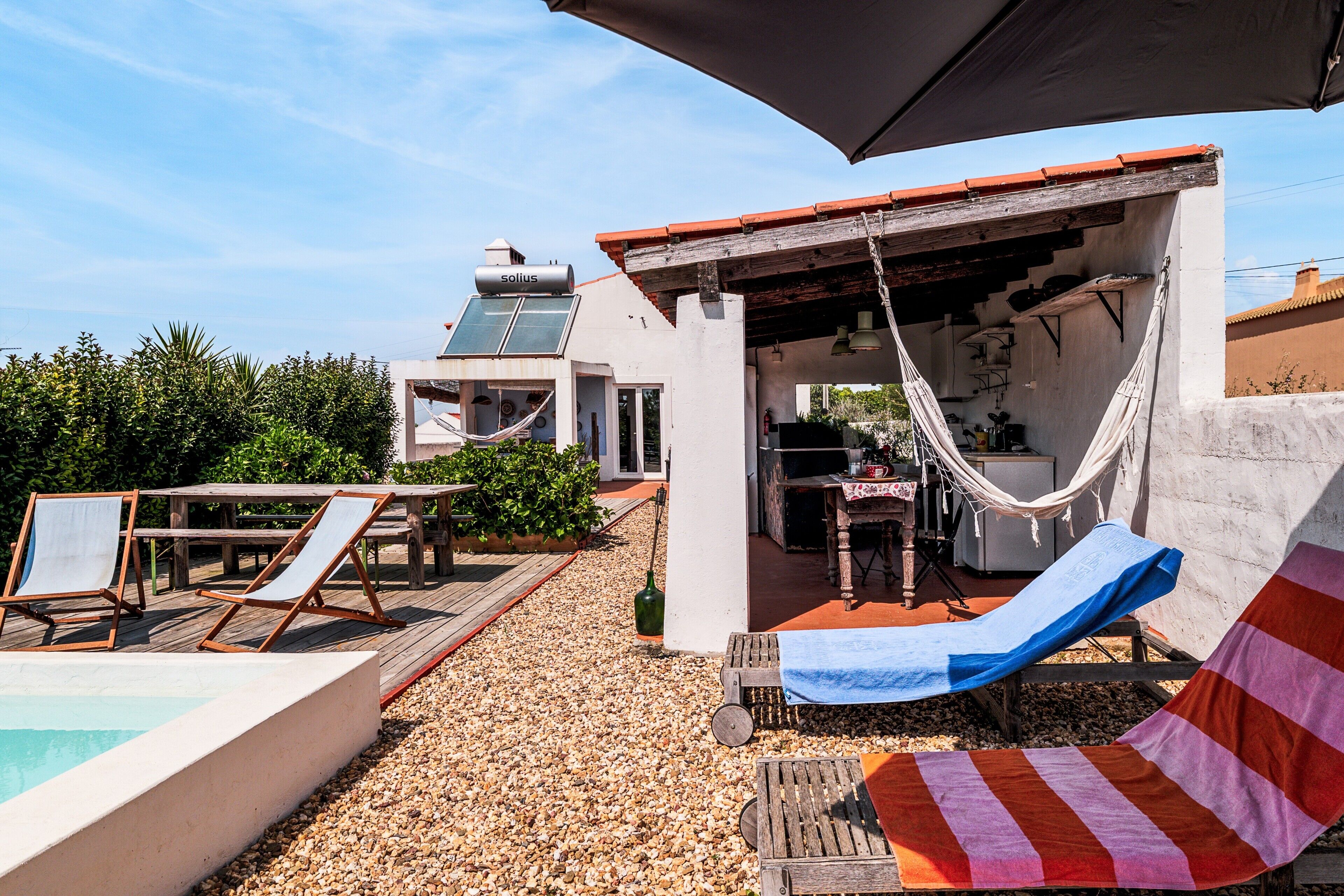 An outdoor patio with a pool, lounge chairs, a hammock, and a covered seating area.