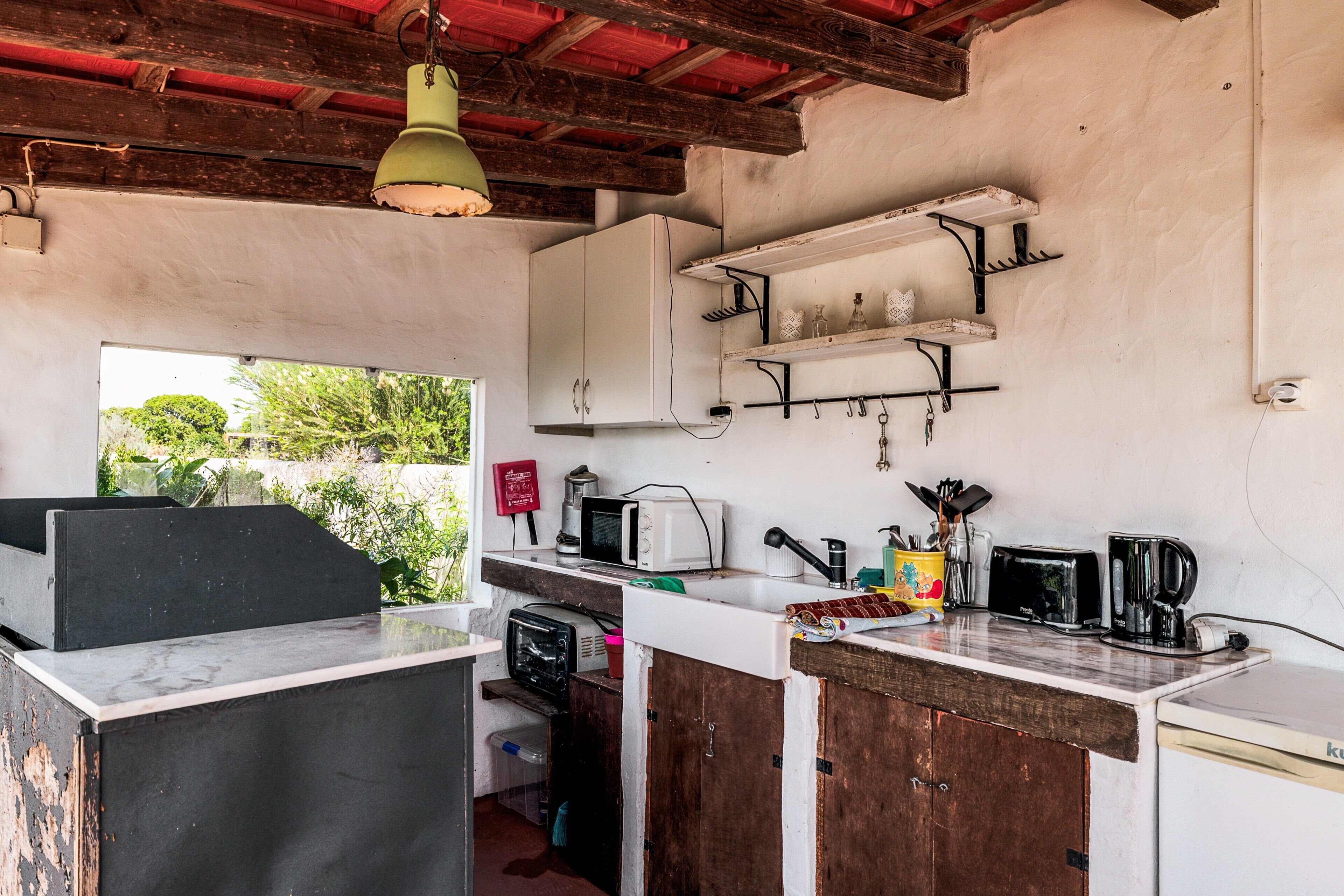 A rustic kitchen with a wooden counter, a white refrigerator, and a hanging light fixture.