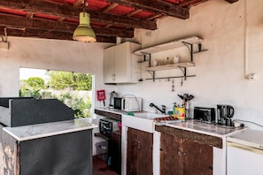 A rustic kitchen with a wooden counter, a white refrigerator, and a hanging light fixture.