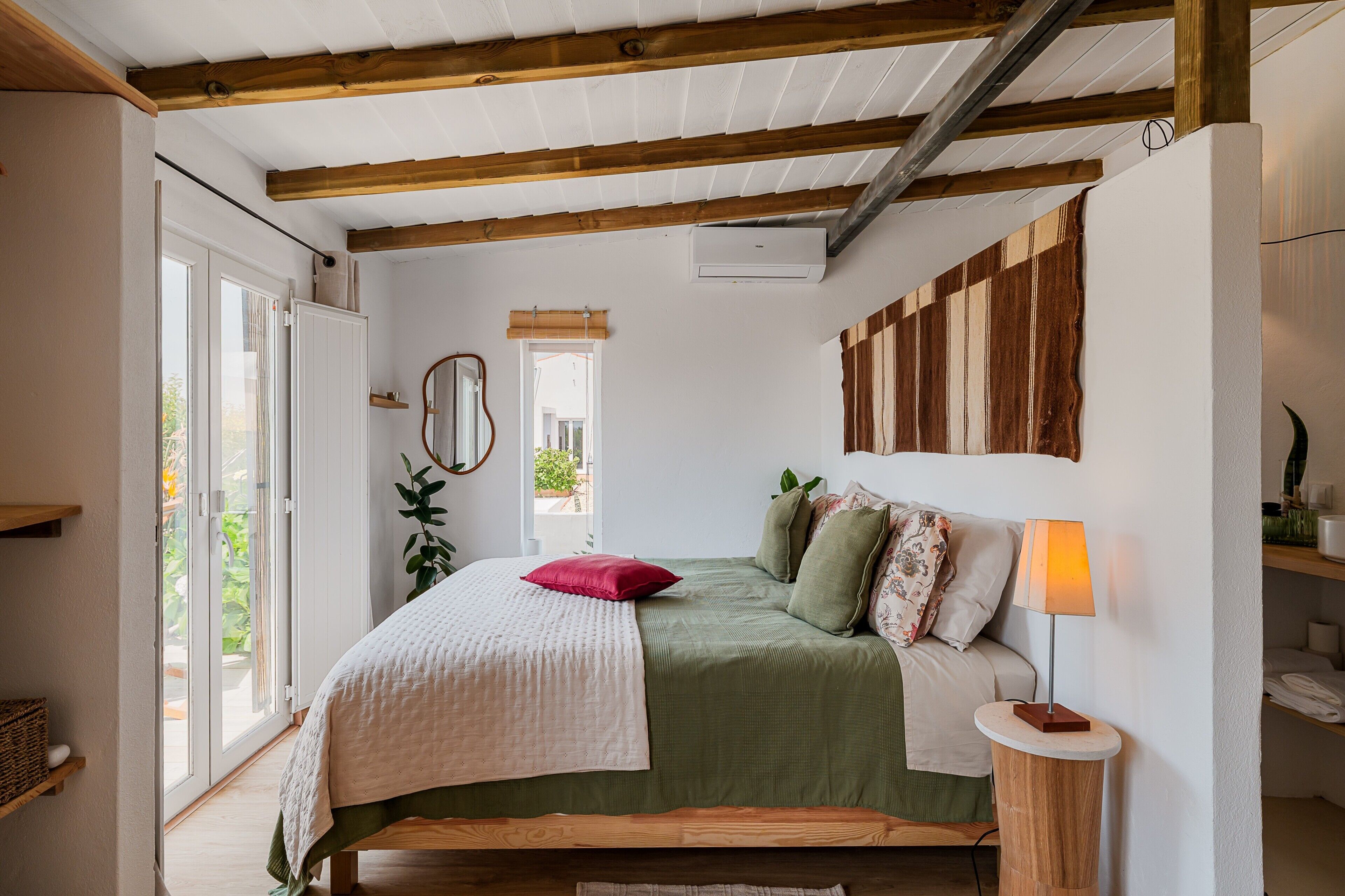 A bedroom with a bed, bedside lamp, and a window.