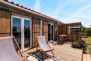 A wooden deck with two lounge chairs and a table, a sliding glass door, and a wooden fence. - Studio Apartment 'Studiolive At Marina Vale Figueira' with Shared Pool, Wi-Fi and Air Conditioning (Melides)