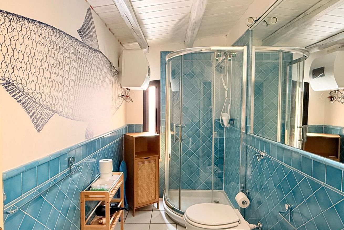 A bathroom with a glass shower enclosure, a toilet, a sink, and a towel rack.