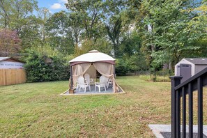 Ein Pavillon mit Tisch und Stühlen in einem Garten.