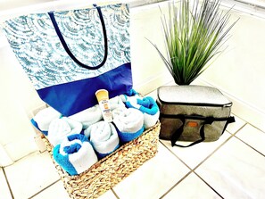 A wicker basket with towels, a sunscreen bottle, a blue tote bag, and a gray suitcase on a tiled floor. - 
The perfect getaway ,ONLY 2 Minutes away from  the beach!!!! (Fort Lauderdale)