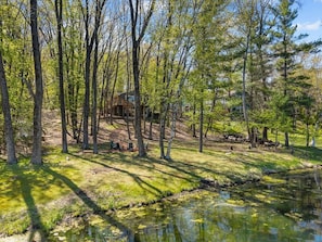 Eine Holzhütte, umgeben von Bäumen und einem kleinen Teich.