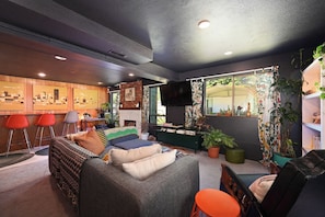 A cozy living room with a sofa, red bar stools, a fireplace, and a TV.