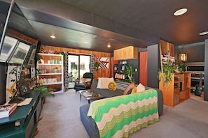 A cozy living room with a sofa, a coffee table, a bookshelf, and a guitar.