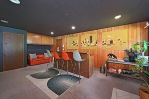 Een moderne woonkamer met een bank, barkrukken en een stadsgezicht muurschildering.