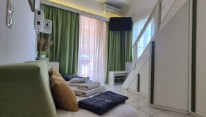Ein Hotelzimmer mit einem Bett, einem kleinen Tisch mit einer Vase, einer Treppe und einem an der Wand befestigten Fernseher.
