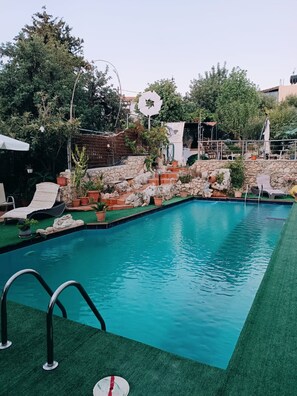 Ein rechteckiger Pool mit Steinmauer und umliegender Bepflanzung.
