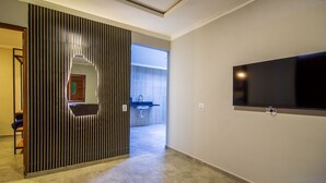 Ett modernt hotellrum med en stor TV, en skjutdörr som leder till badrummet och utsikt över omgivningarna.