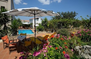 A pool area with chairs and an umbrella, surrounded by greenery and flowers. - Bicorna Chania Pool Escape - Yellow Room 1 (Apokoronas)