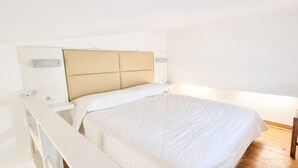 Una cama con cabecera, mesitas de noche y suelo de madera.