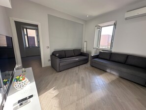 Un salón moderno con un sofá gris, un televisor de pantalla plana y suelo de madera.