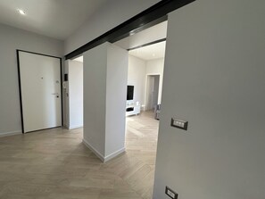 A hallway with a white door, a light switch, and a wall socket.