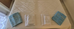 A bed with a quilted white mattress, two folded towels, and a blue towel on the side. - Bicorna Chania Pool Escape - Silver Room 3 (Apokoronas)