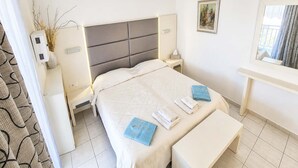Una habitación de hotel con cama, mesitas de noche, un espejo y una ventana con cortinas.
