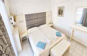 A hotel room with a bed, bedside tables, a nightstand, a mirror, and a window with curtains. - Bicorna Chania Pool Escape - Silver Room 3 (Apokoronas)