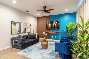 A modern living room with a grey sofa, blue armchairs, a wooden coffee table, and a ceiling fan. - 3-bedroom Townhome with High Speed WIFI (Bullard)