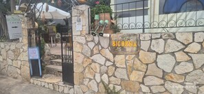 Eine Steinsäule mit einem Schild, auf dem 'BICORNIA' steht, und einem Schild für 'BICORNIA Zimmer', das nach rechts weist.