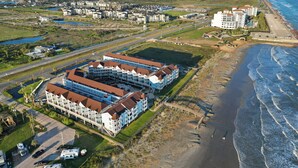 A coastal hotel with multiple buildings, a beach, and a view of the ocean.