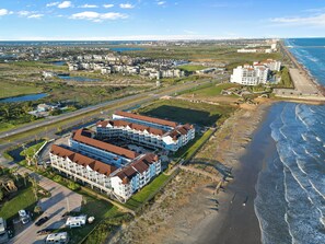 A coastal hotel with multiple buildings, a beach, and a view of the ocean.