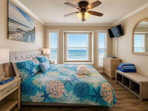 Ein Schlafzimmer mit einem Bett, einem Deckenventilator, einem Fernseher, einem Schminktisch, einer Bank und einem Gemälde.
