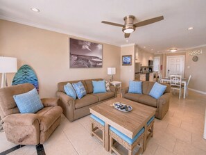 Ein Wohnzimmer mit einer Couch, Sesseln, einem Couchtisch und einem Deckenventilator.