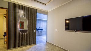 Um interior moderno com uma TV na parede, uma porta deslizante com design exclusivo e um vislumbre de um banheiro com uma pia.