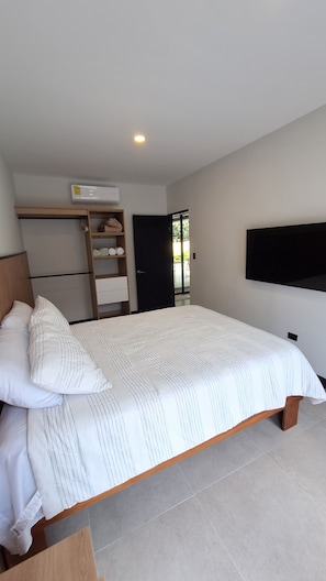 Un dormitorio con cama, televisión, armario y aire acondicionado.