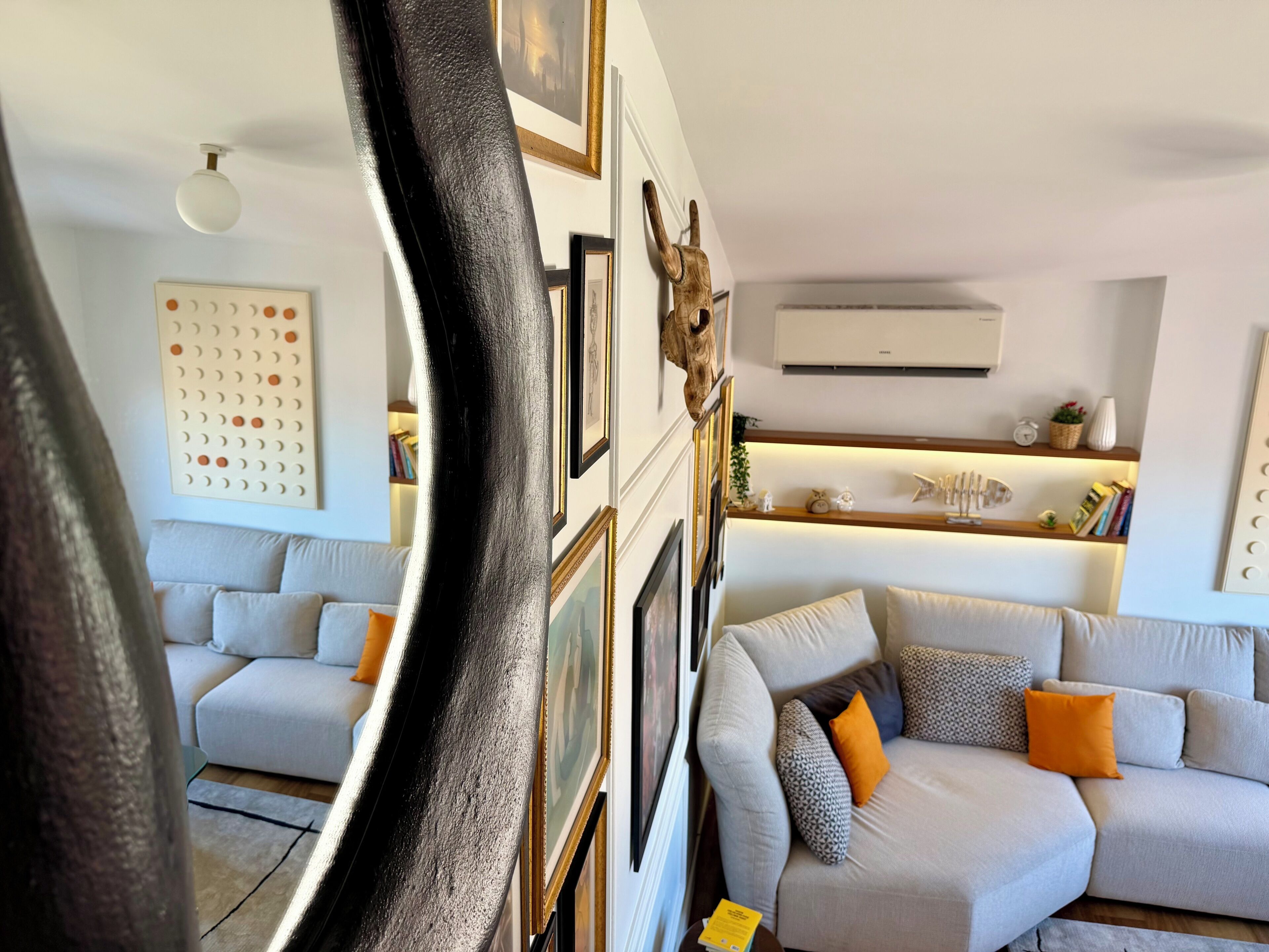 A living room with a sofa, a coffee table, and a wall-mounted shelf with decorative items.